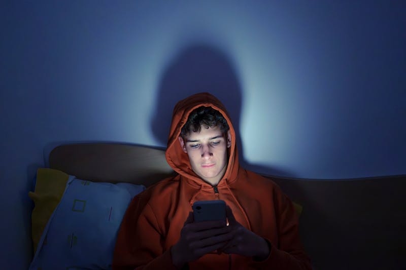 teenage boy texting someone at night