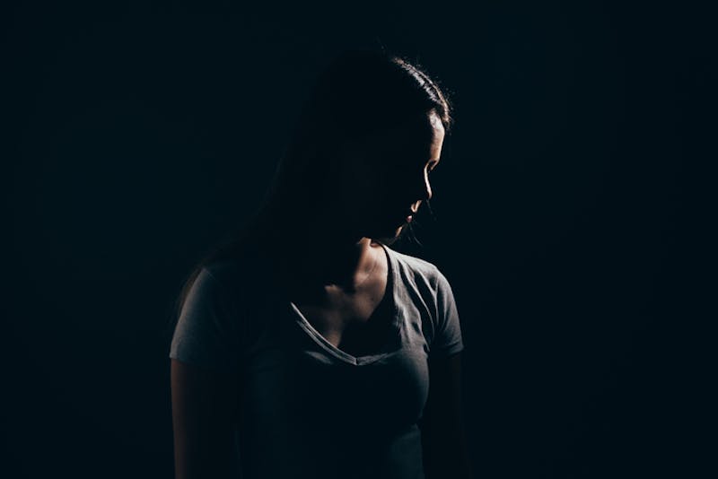 A sad woman standing in the dark