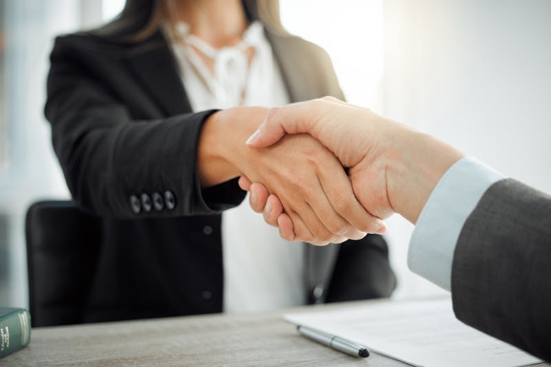 Women shaking hands across a desk