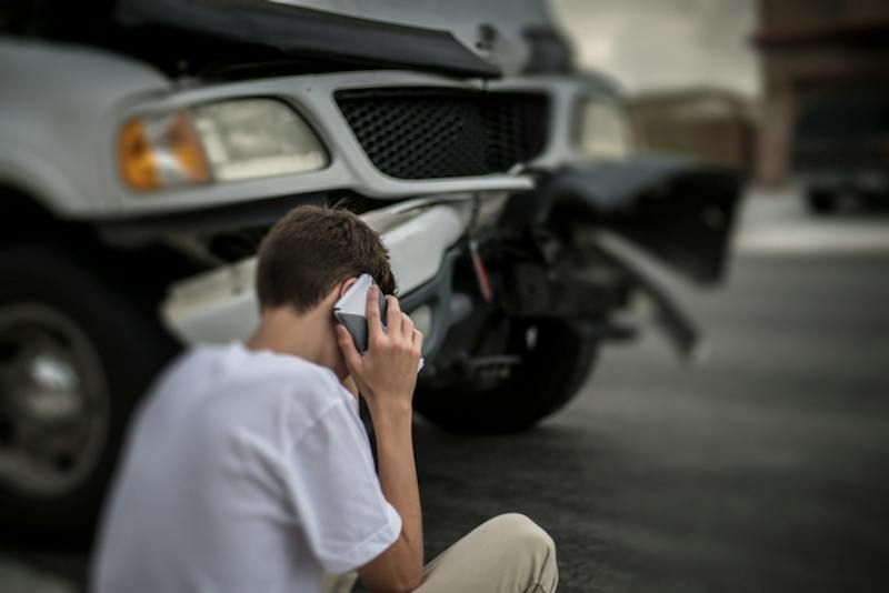 A man on phone by crashed car