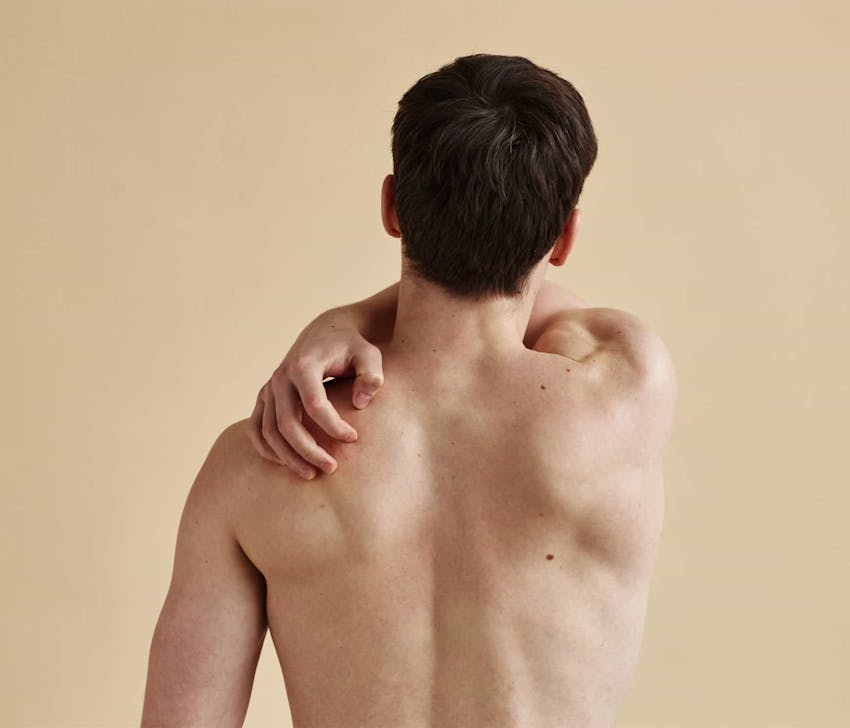 man scratching his back