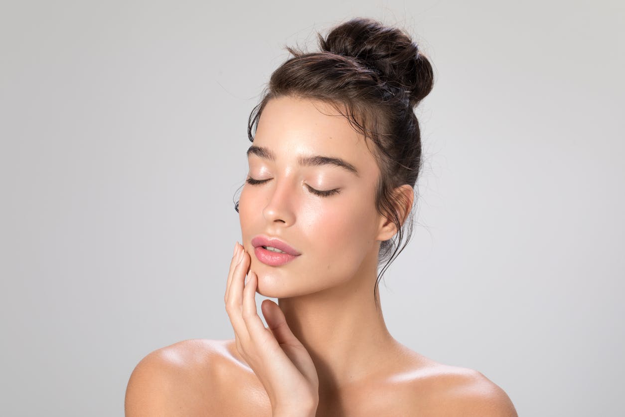A woman with her hair in bun closing her eyes
