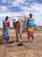Three people digging semicircular bunds.