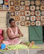 Be Marie Wilvinah, president of the artisan women’s group working in Mahalevona, prepares raffia stems by stripping them into fibers for weaving.
