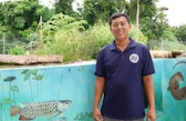 A man standing in front of a turqouise half wall full of paintings of different animals