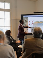 A person presenting to a dozen of people in a nicely lit up room