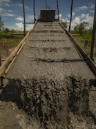 The sluice washing system channels a mixture of sand and water to accumulate gold