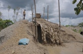 A miner next to a sand mound and a sluice washing system used to accumulate gold