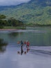 Two residents wade across a river in northeastern Madagascar, carrying goods on a pole between villages and fields.