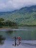 Dorfbewohner*innen durchqueren einen Fluss im Nordosten Madagaskars und transportieren Güter.