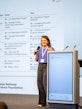 Dominique Schmid speaks on stage with a microphone during her presentation at the 2026 SOR4D Conference.
