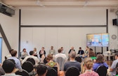 Vilma speaks into a microphone during a panel discussion, with panelists and audience members seated around the room at the 2026 SOR4D Conference.