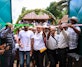 A group cuts a pink ribbon at the entrance to the Mirohy Center in Masindrano, framed by open turquoise gates and a leafy arch, while other participants look on.