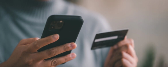 Osoba z telefonem oraz kartą płatniczą