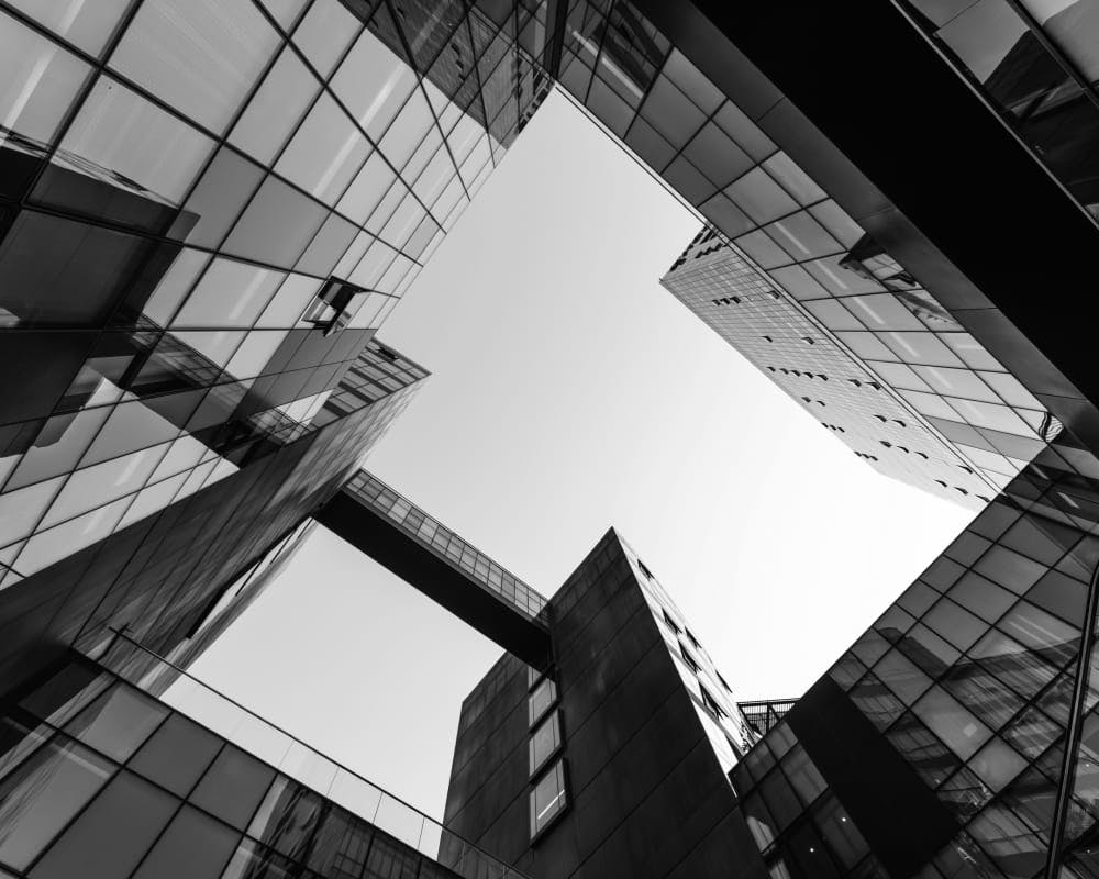 greyscale of looking up in the center of a bunch of buildings