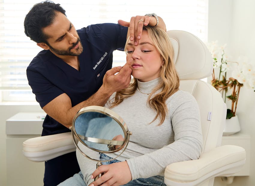 Dr. Alemi touching client's face while holding handheld mirror