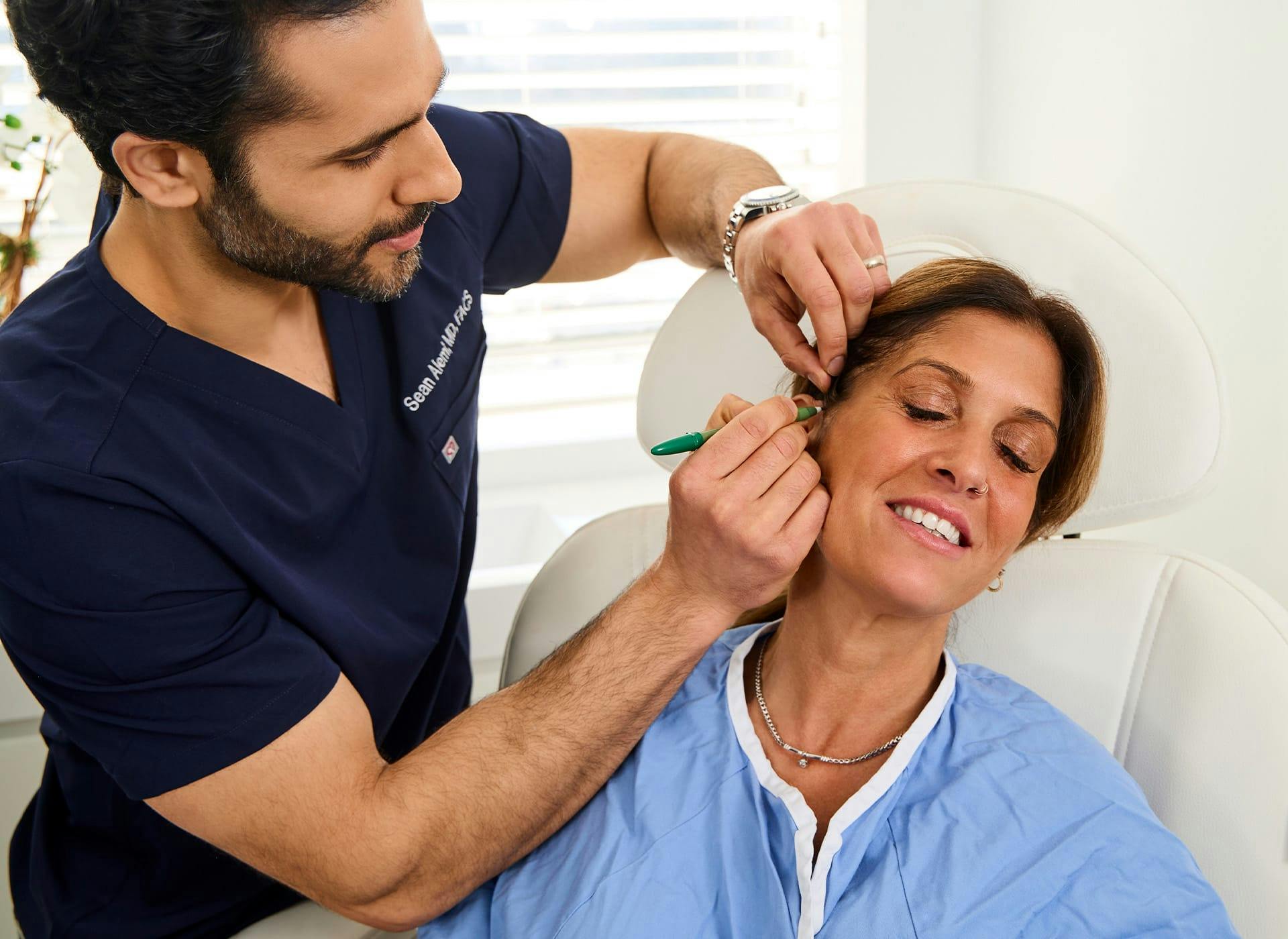 Dr. Alemi marking on client's face with marker