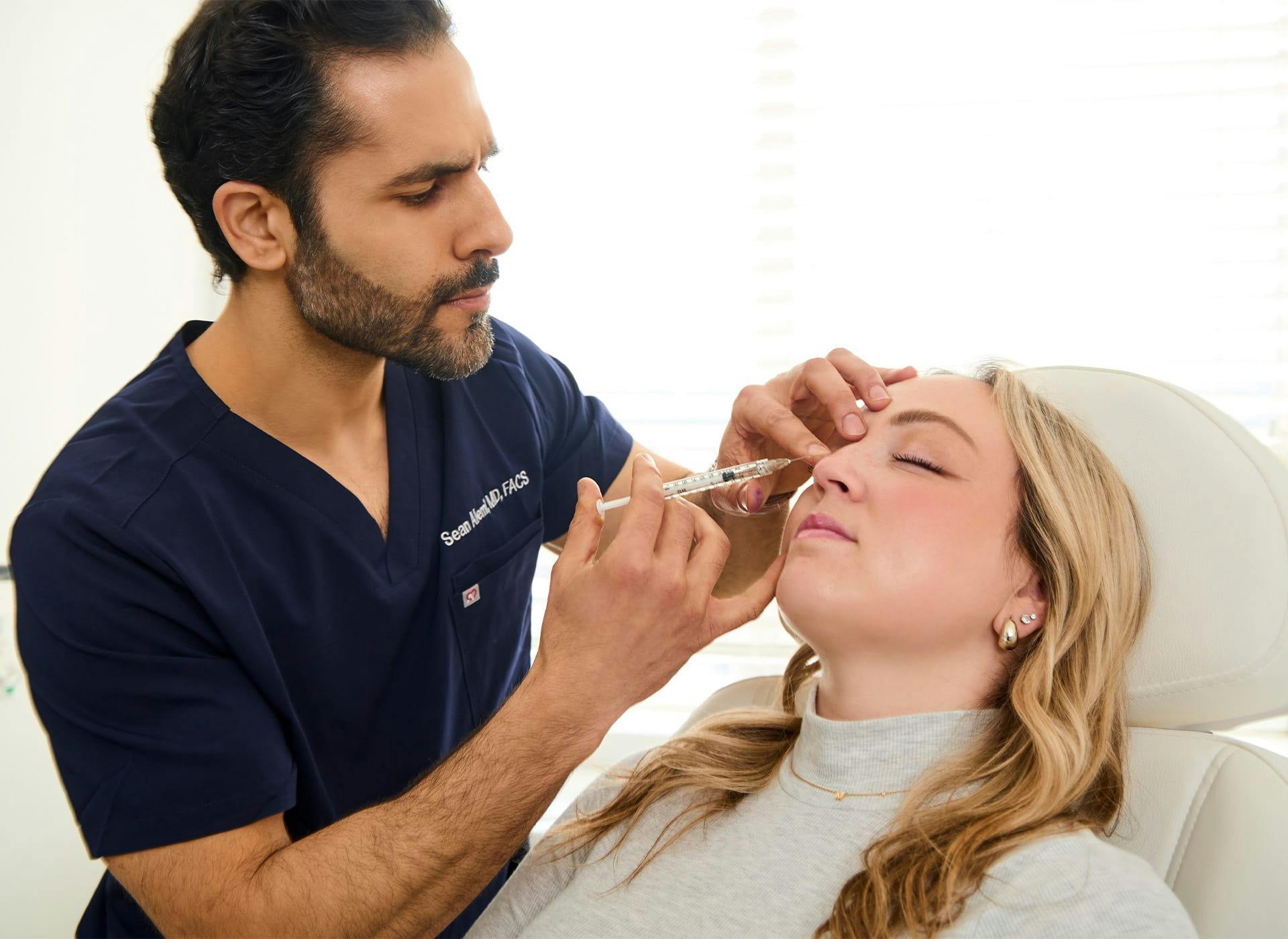 Dr. Alemi injecting syringe into client's forehead
