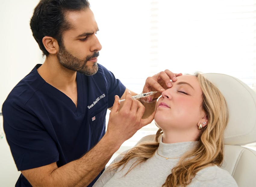Dr. Alemi injecting syringe into client's forehead