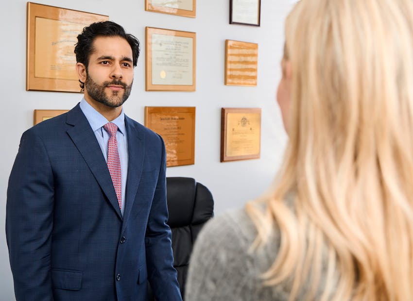 Dr. Alemi in suit standing in front of his certificates