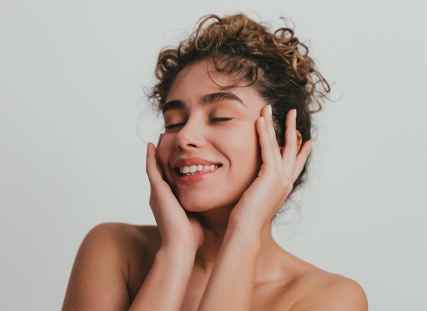 woman with curly hair smiling with eyes closed