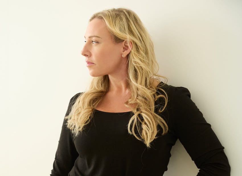 woman with blonde hair in black top looking to the left