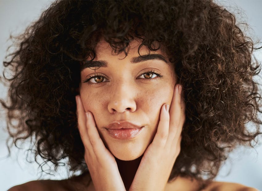 woman with afro with hands around her face