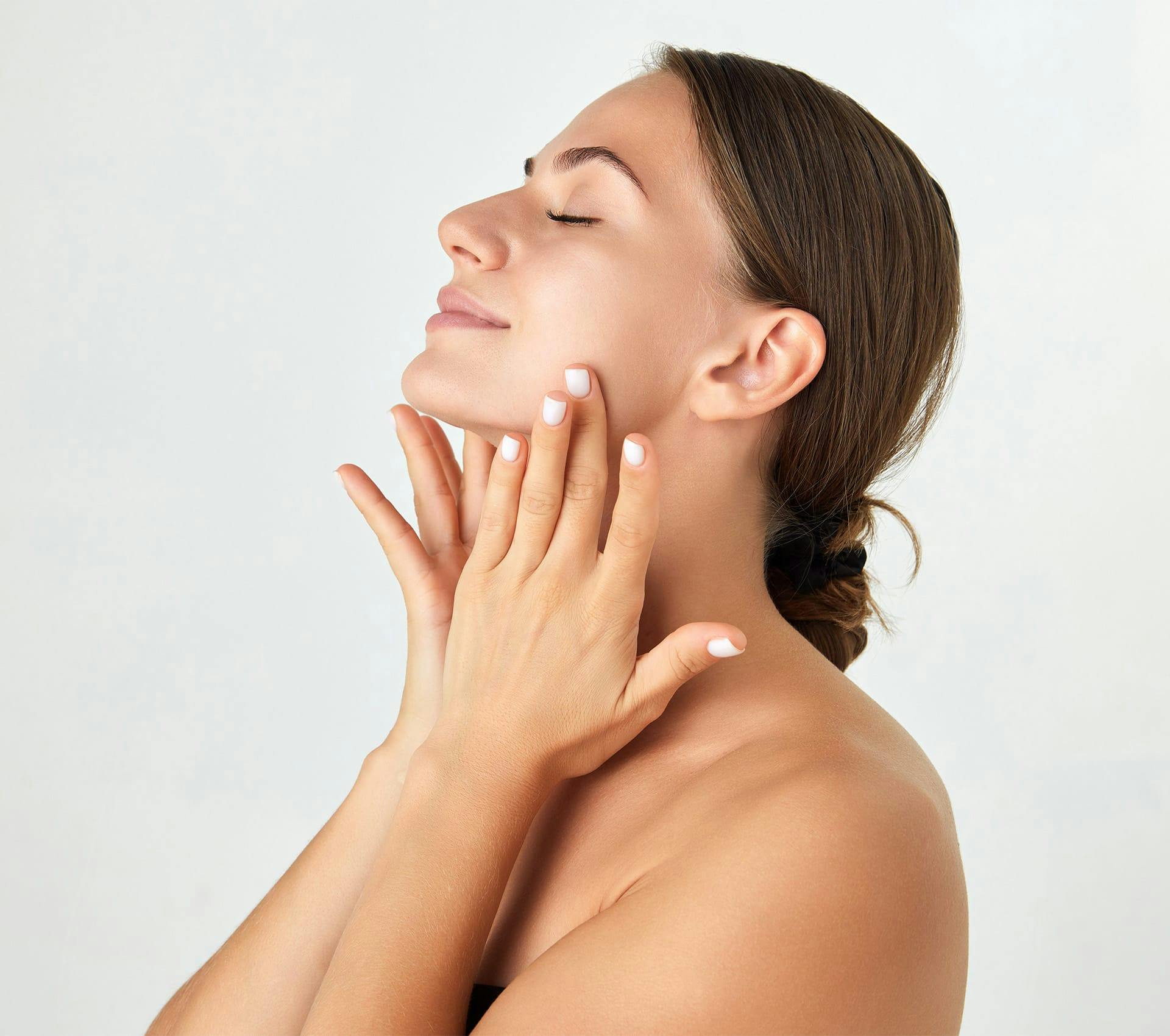 woman touching her face with low bun hairstyle