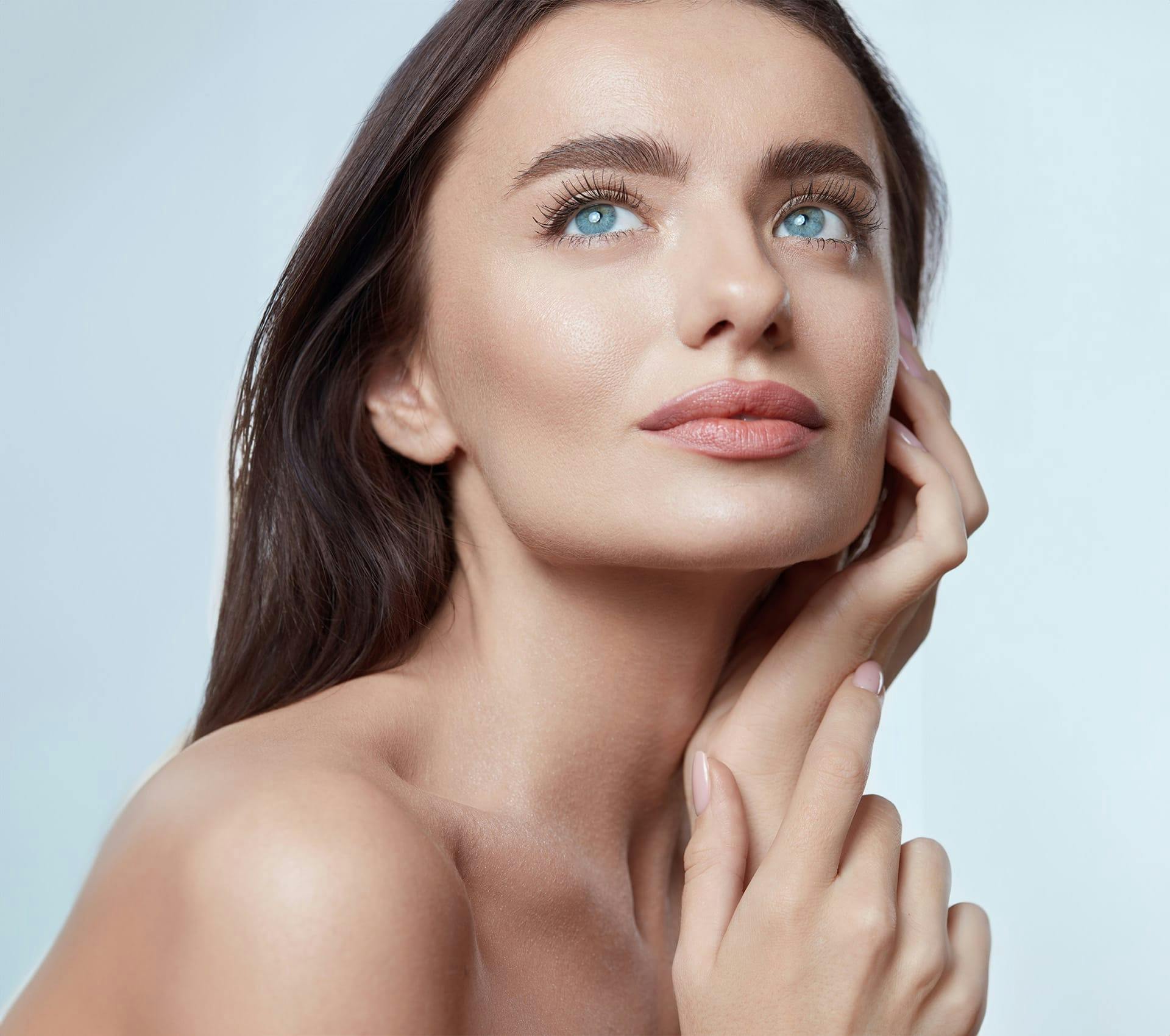 woman with blue eyes looking up with hand on her face