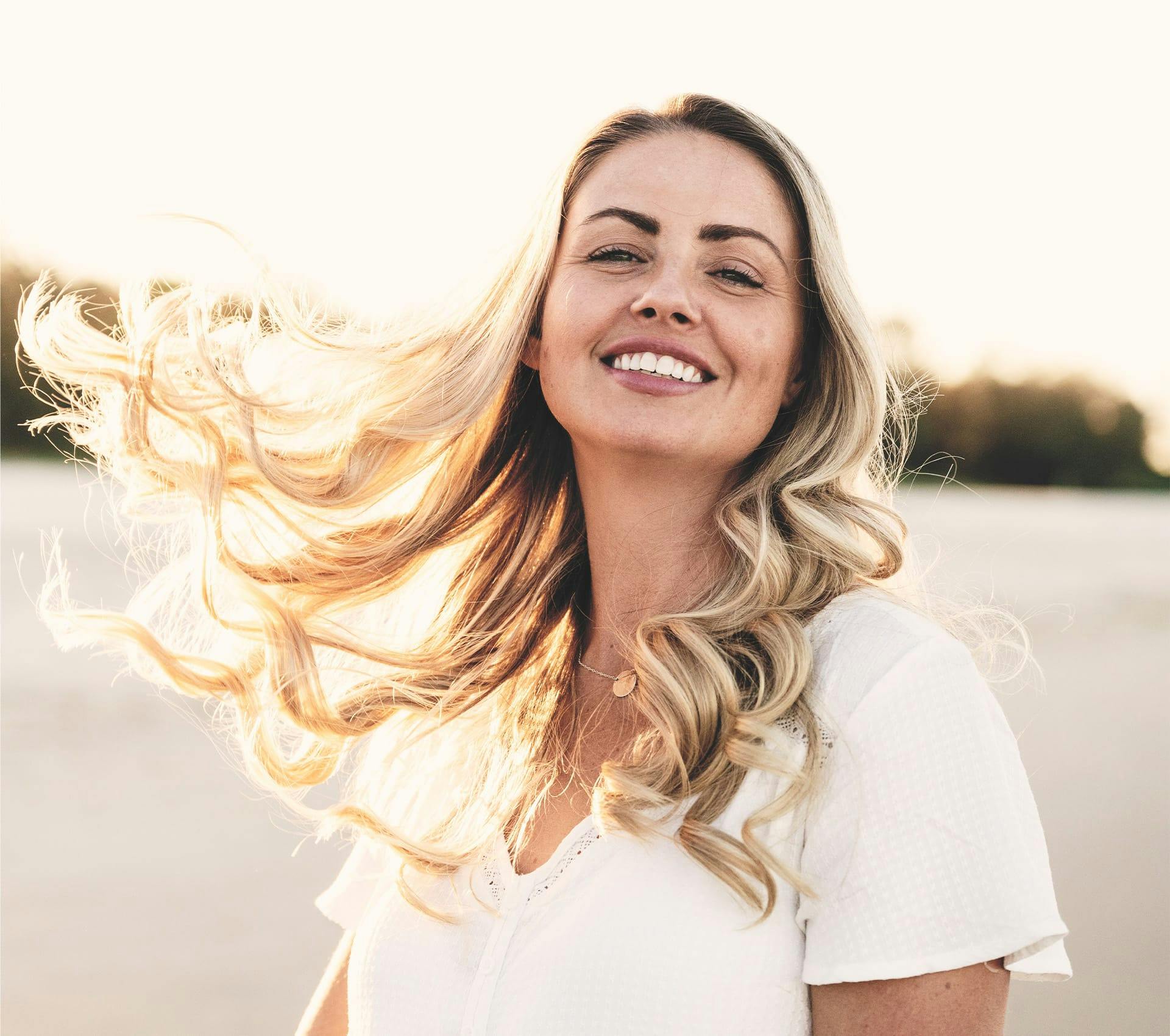 woman smiling while her hair flows in wind