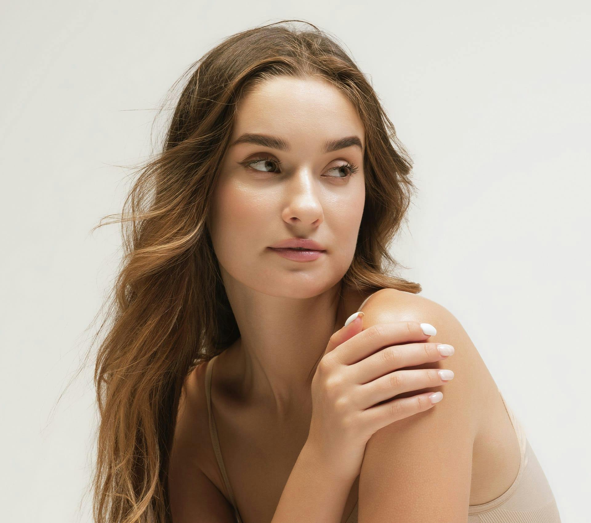 woman looking to the right with her hand touching her shoulder