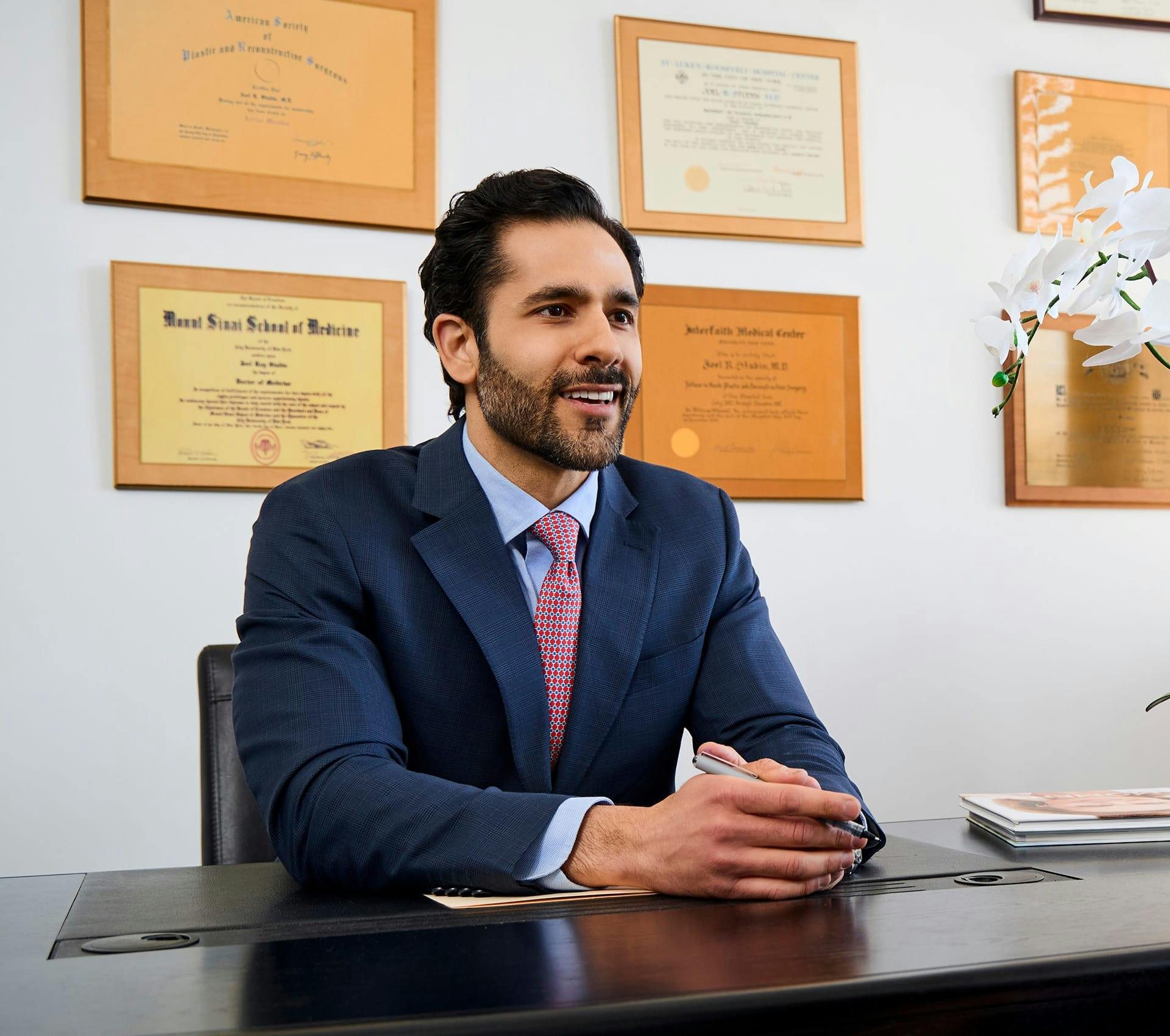 Dr. Alemi in suit sitting at desk