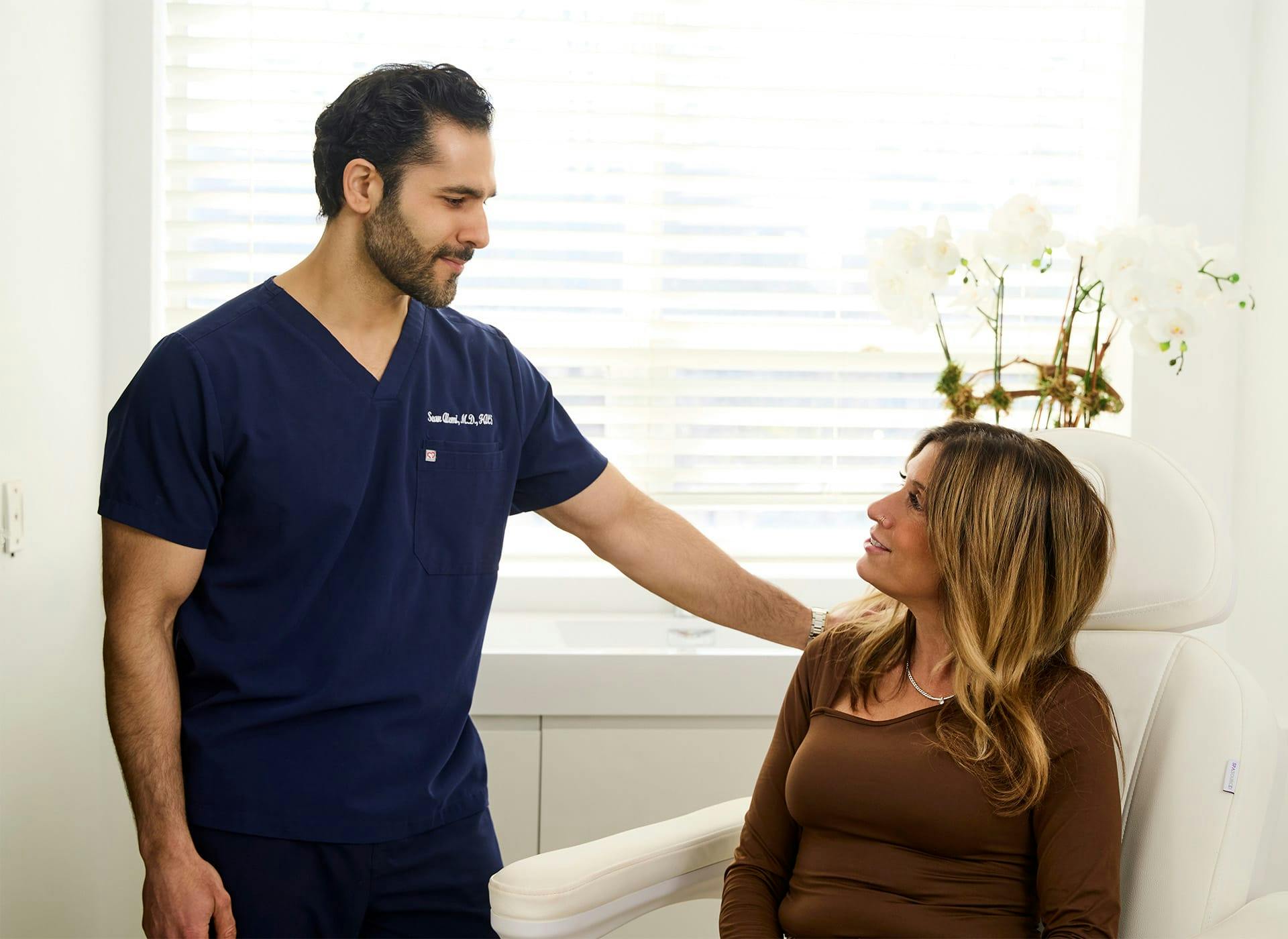 Dr. Alemi speaking to client as she sits in chair