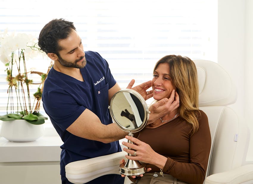 Dr. Alemi touching client's cheeks while she smiles