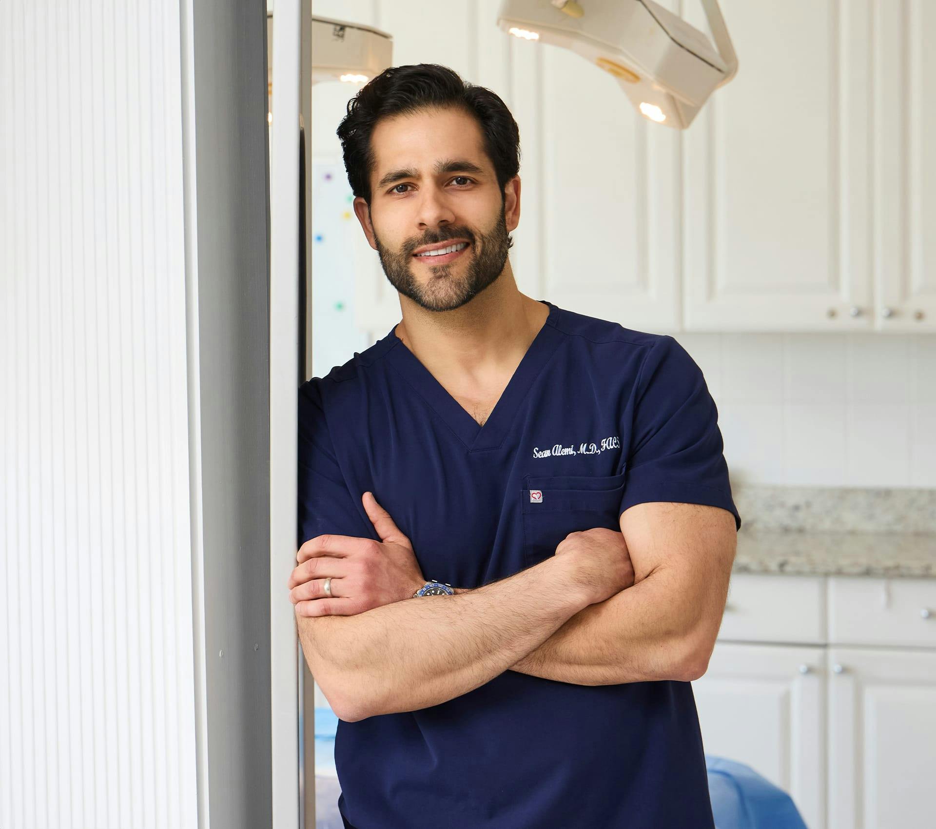 Dr. Alemi crossing his arms leaning on door arch