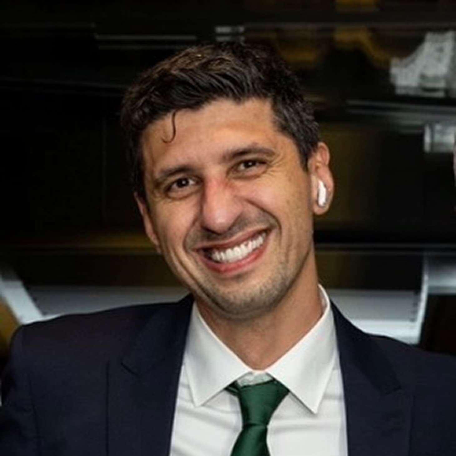 A well-dressed man in a suit and tie, smiling broadly for the camera