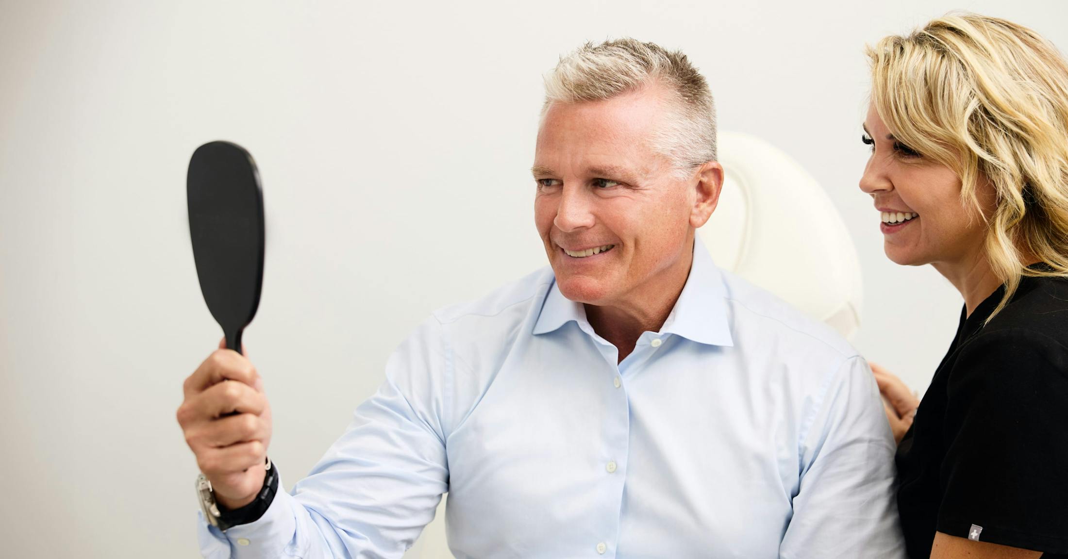 man looking at himself in a handheld mirror