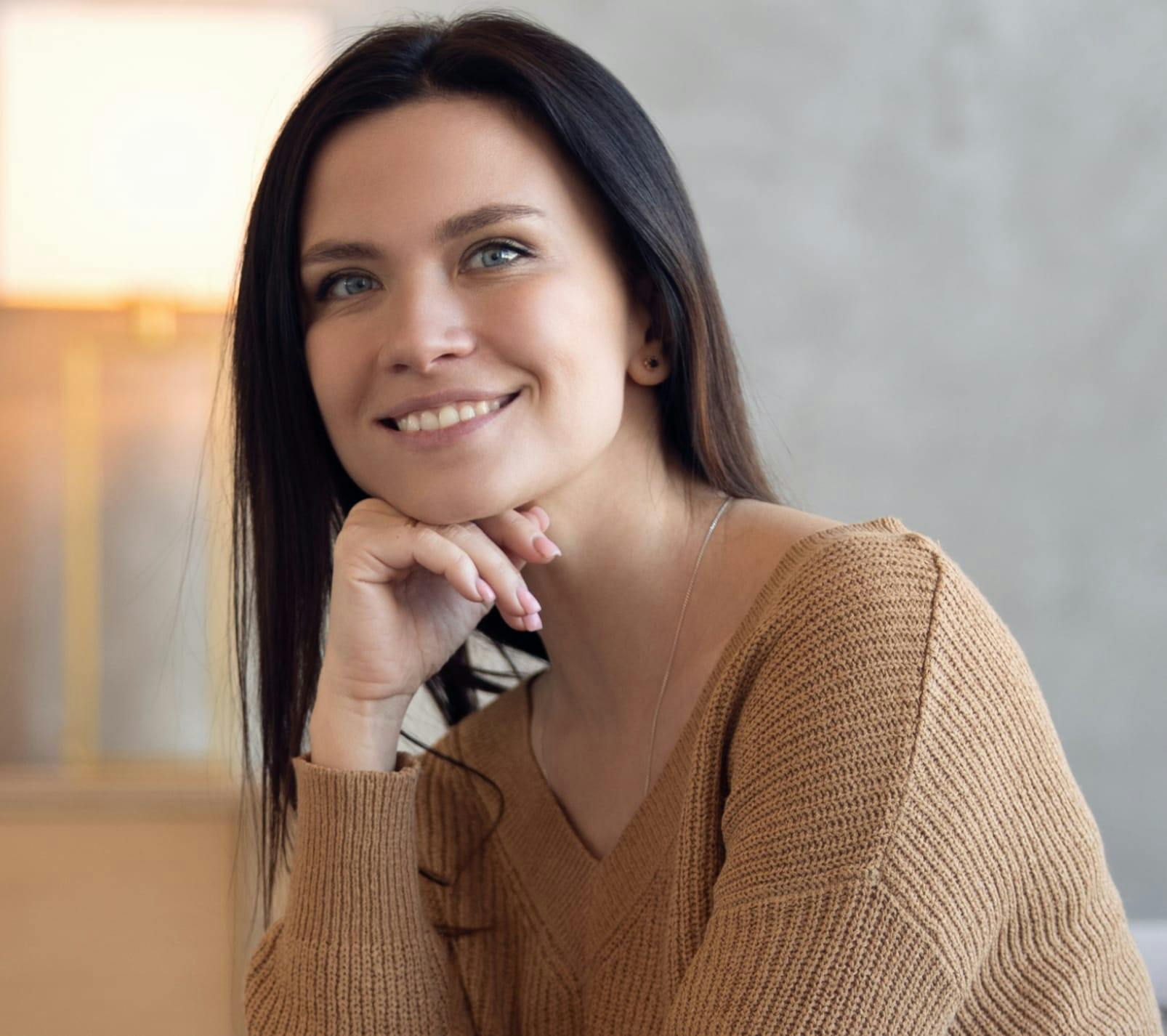 woman with long dark hair resting her face on her chin