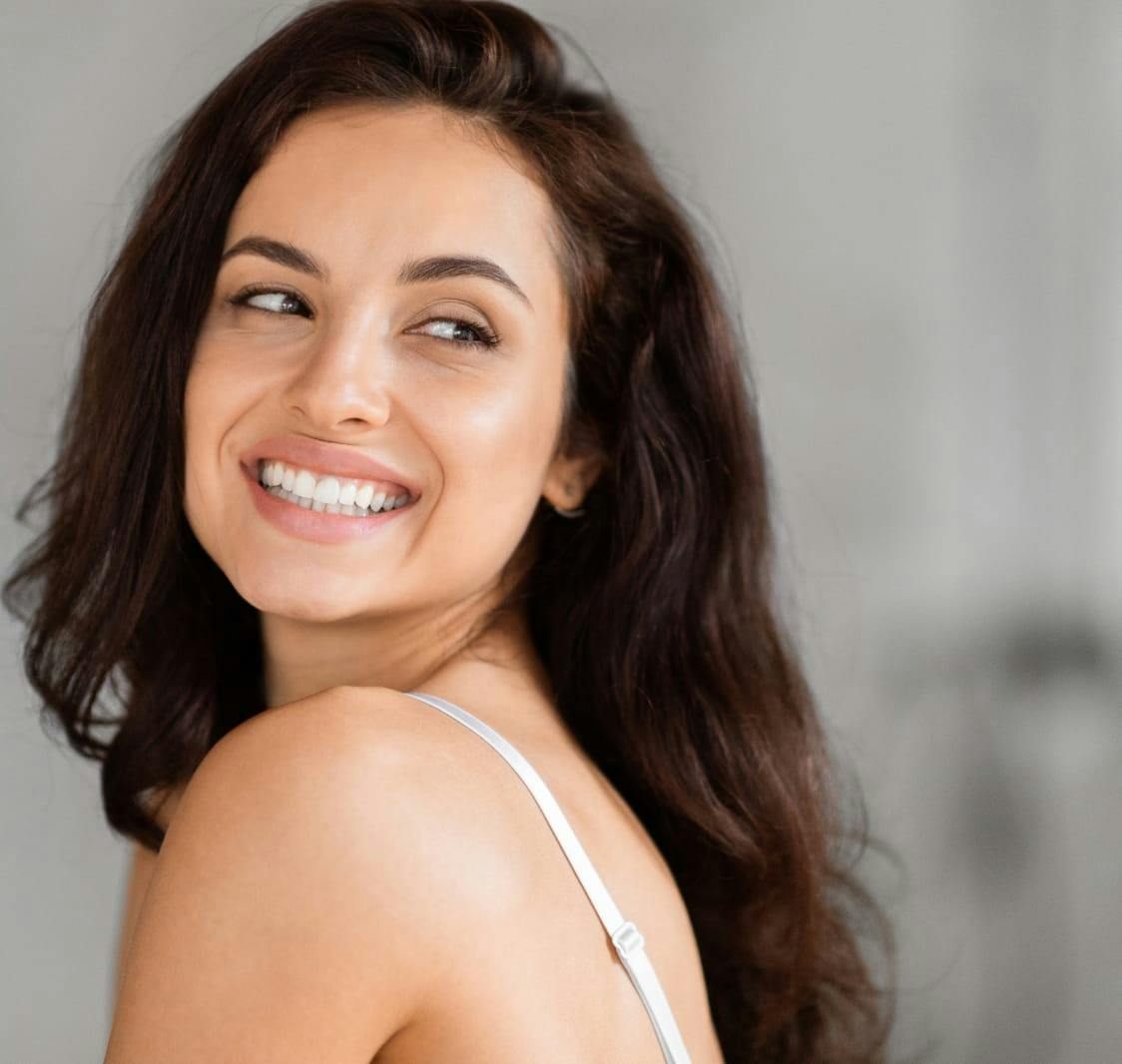 woman with long dark hair smiling over her shoulder