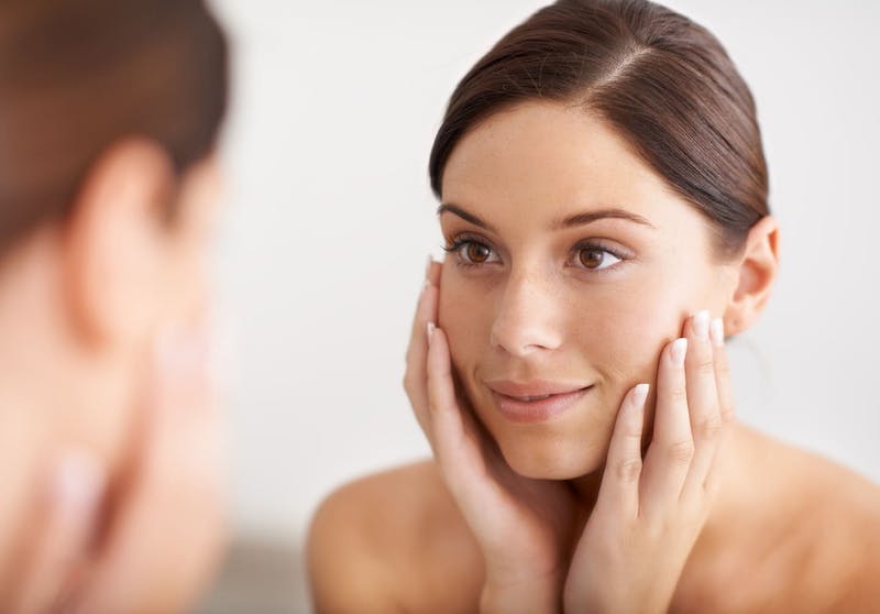 woman touching her face looking in the mirror