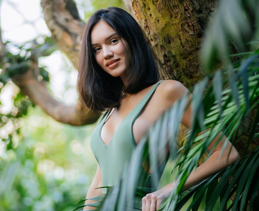 woman in a green bodysuit outside near trees