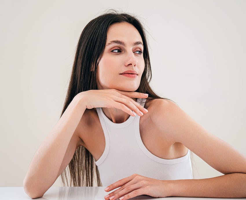 woman with long dark hair wearing a white tank top