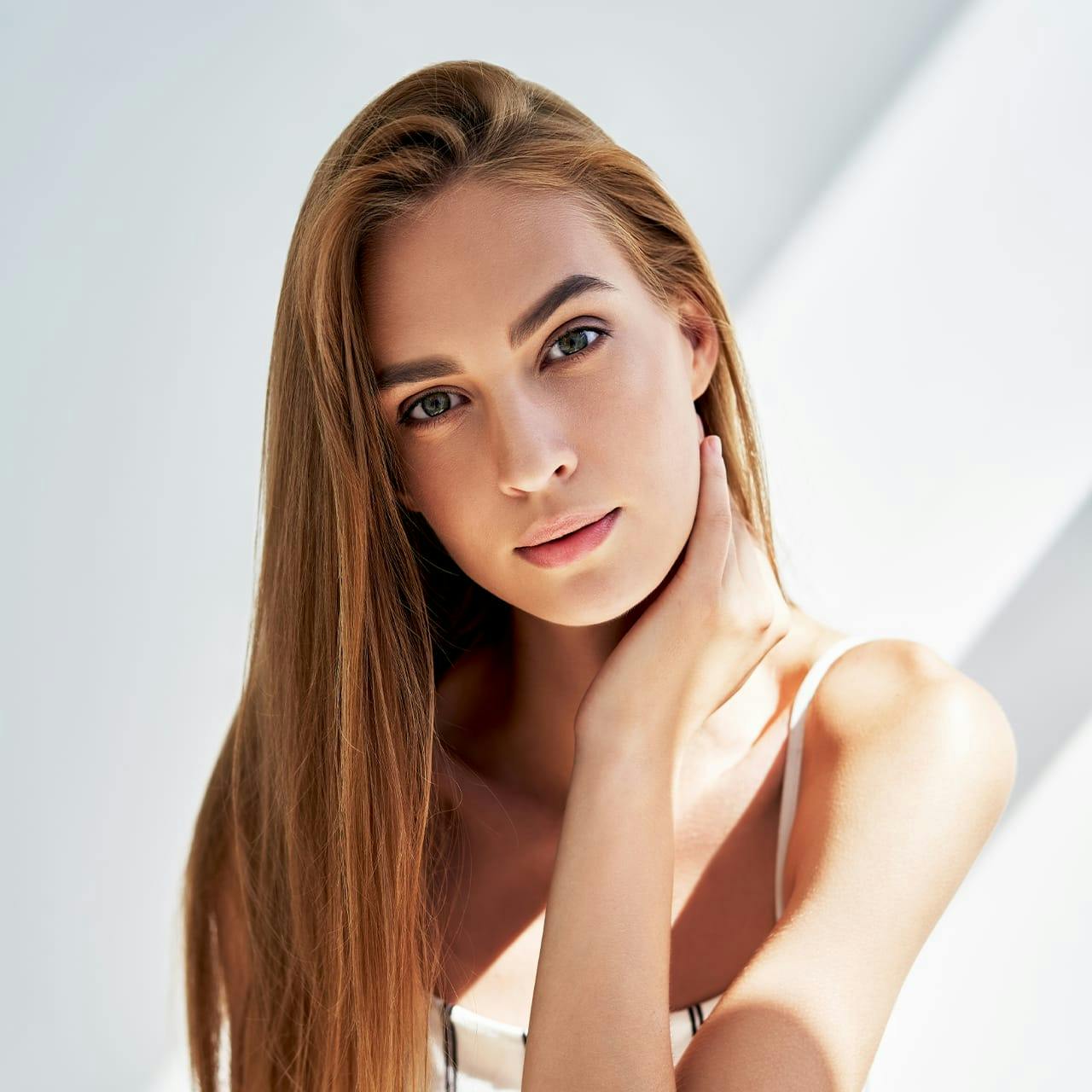 woman with red hair touching her neck