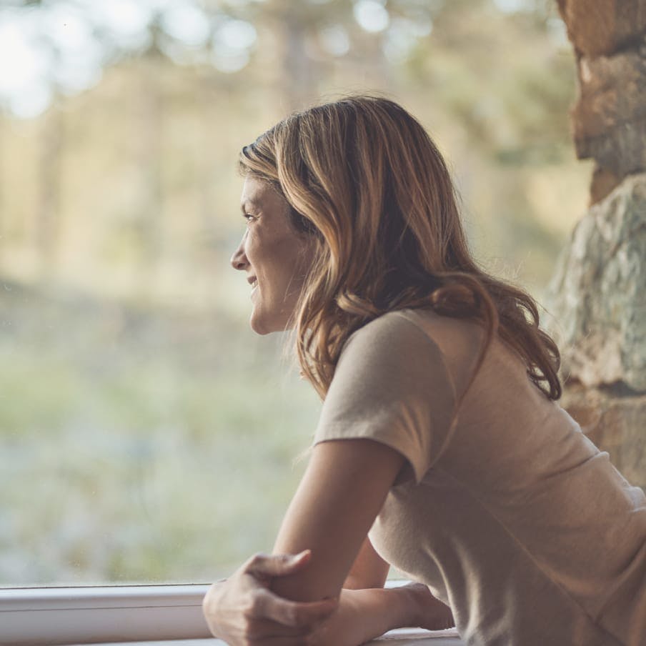 woman leaning on fence looking out to the forest