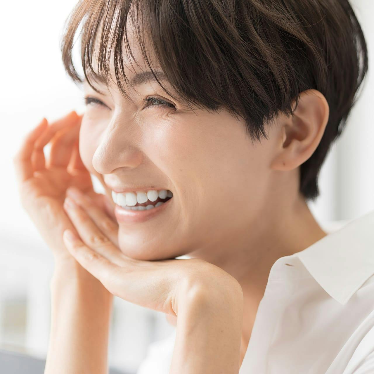 smiling woman with hands on face