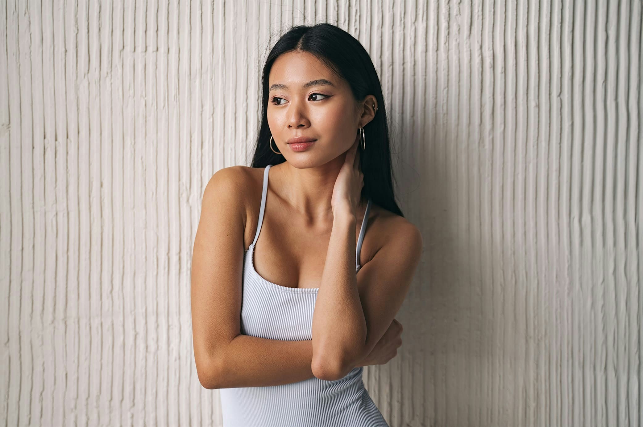 woman holding neck standing next to wall