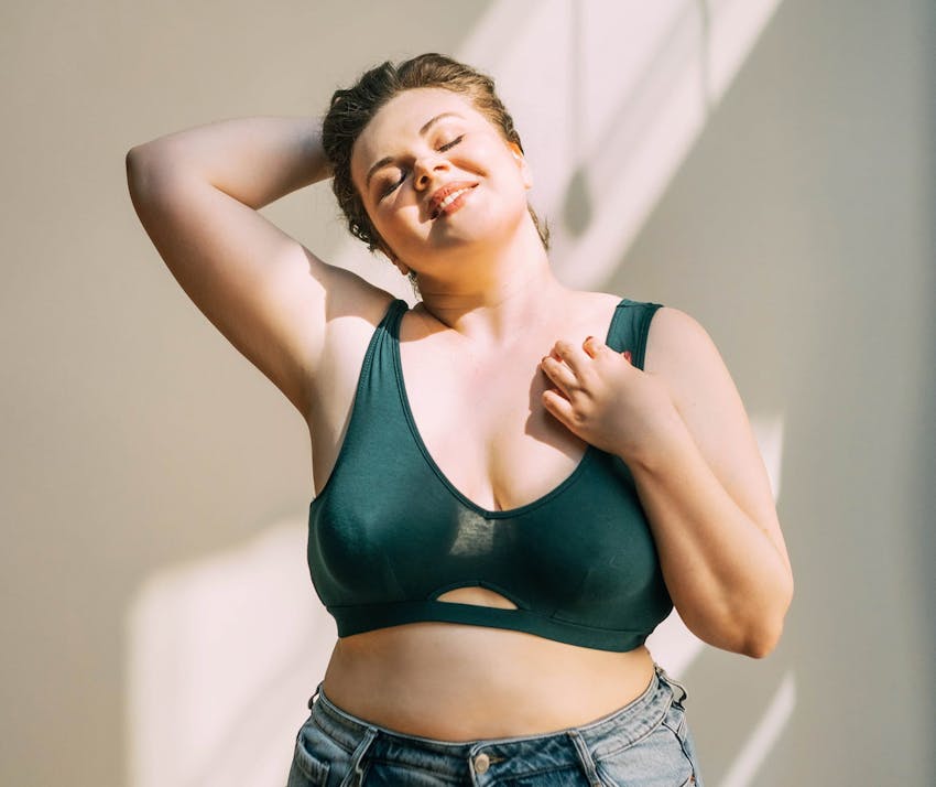 Woman with a bra on and a hand to her head