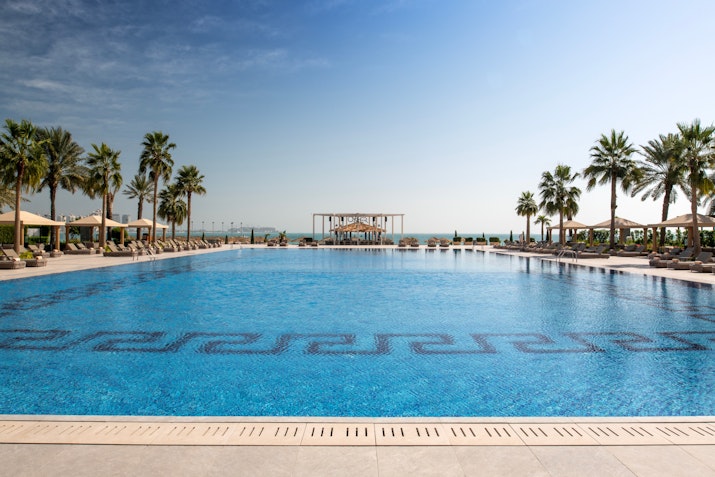 Spacious outdoor pool with a view of palm trees and the ocean