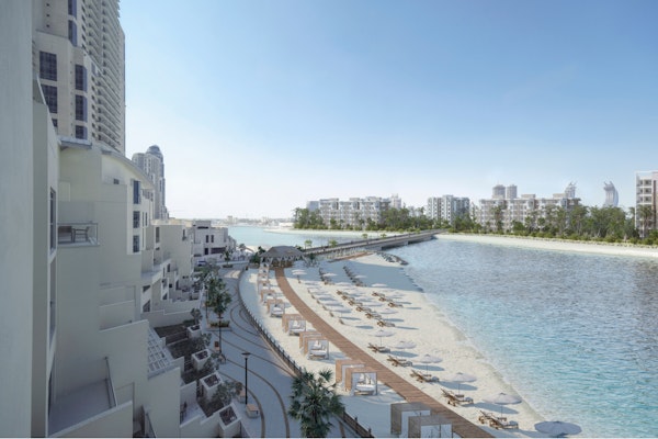 Hilton Doha The Pearl with Privilee Beachfront resort with lounge chairs and a scenic walkway along the water.