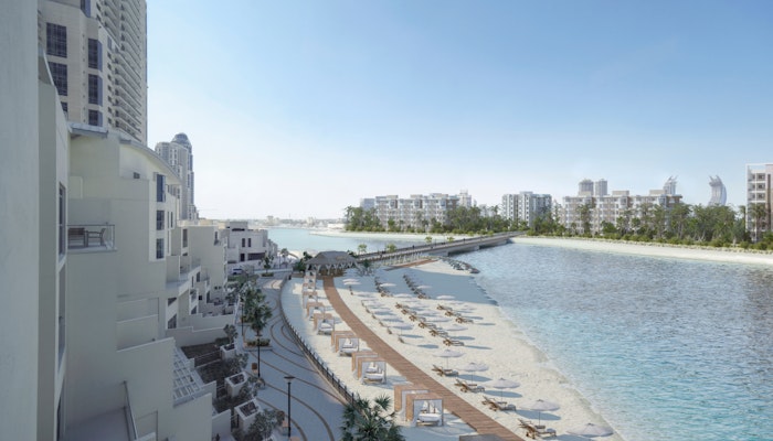 Hilton Doha The Pearl with Privilee Beachfront resort with lounge chairs and a scenic walkway along the water.